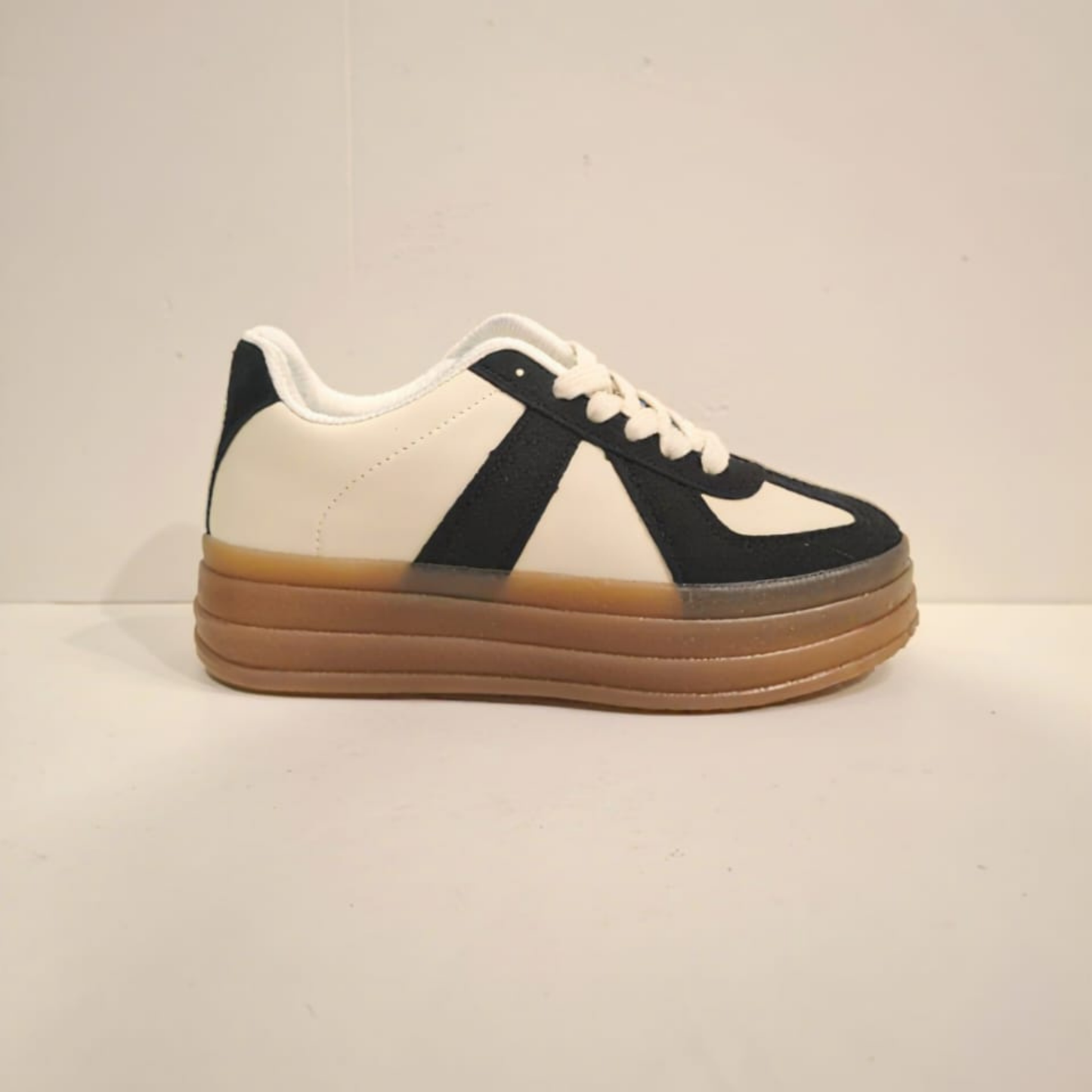 Zapatilla urbana para mujer en color crema con refuerzos y detalles en gamuza negra, cordones blancos y una suela de plataforma ancha en goma color café.vime moda chile