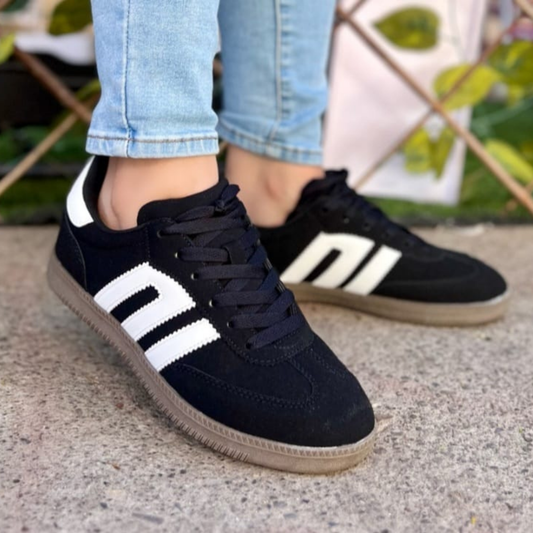 Zapatilla urbana estilo samba de color negro con franjas laterales blancas y detalle en el talón, suela de goma café oscura, diseño clásico y versátil para mujer.vime moda chile