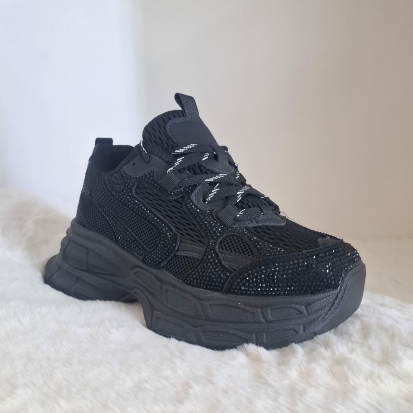 Zapatilla urbana estilo chunky para mujer en color negro, con detalles de pequeños brillos (strass) en la superficie, malla transpirable y una plataforma robusta totalmente negra.vime  moda chile 