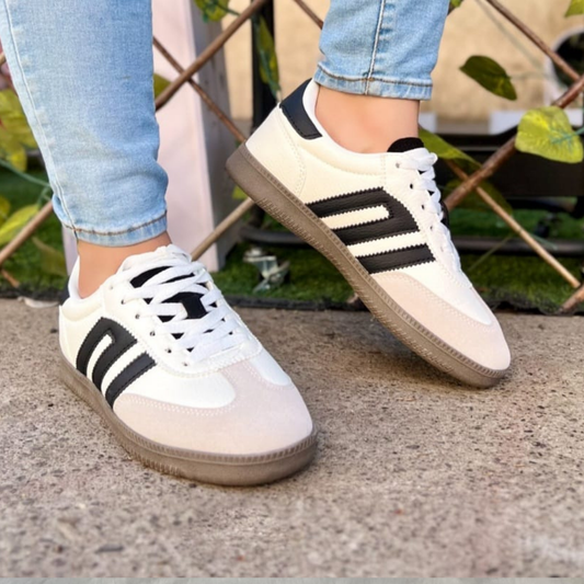 Zapatilla estilo samba urbana de color blanco con franjas laterales y talón en negro, puntera de gamuza gris claro y suela de goma café, estilo retro para mujer.vime moda chile