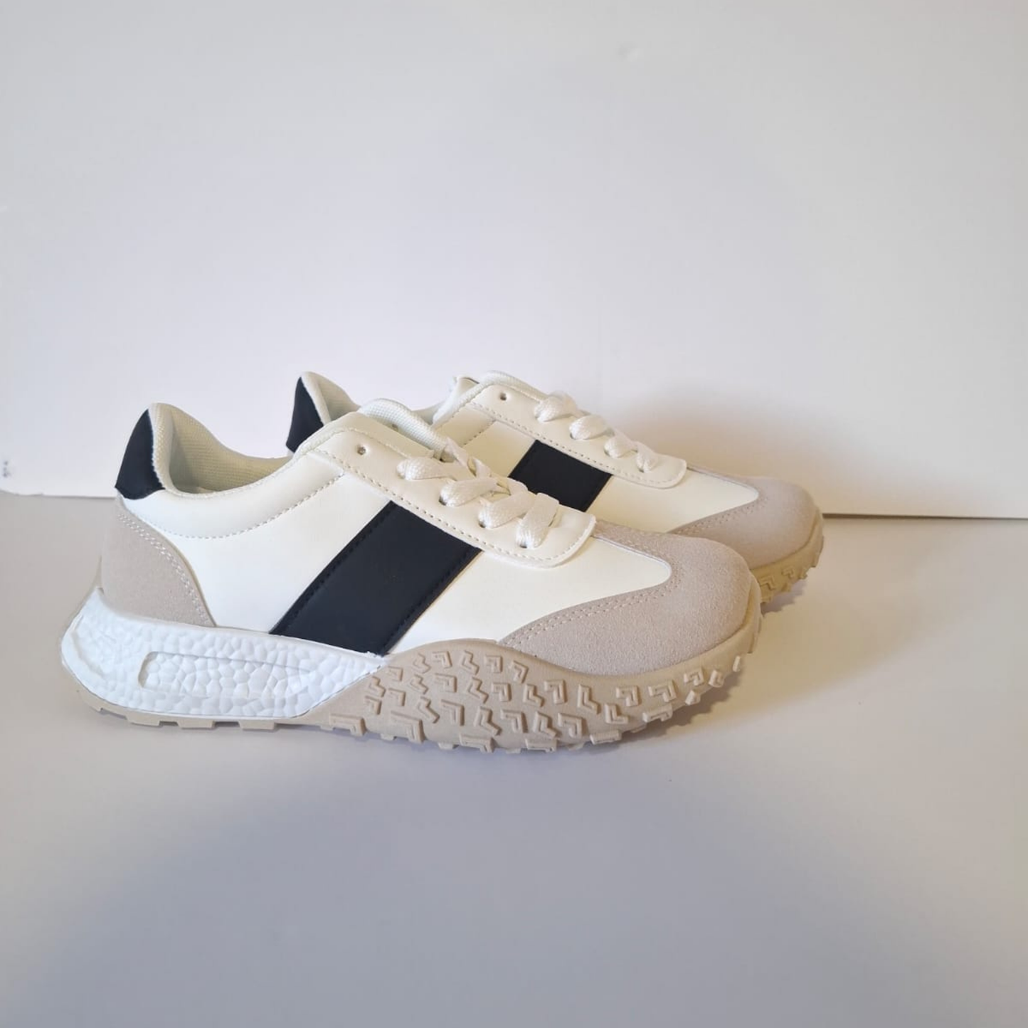 Zapatilla blanca urbana para mujer en color blanco con una franja lateral negra, puntera reforzada en gamuza gris y una distintiva suela de goma color crema con textura de relieve.